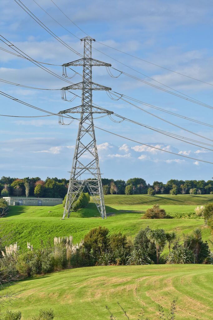 Steel transmission tower above green fields