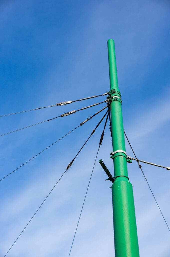 Green steel utility pole with power lines