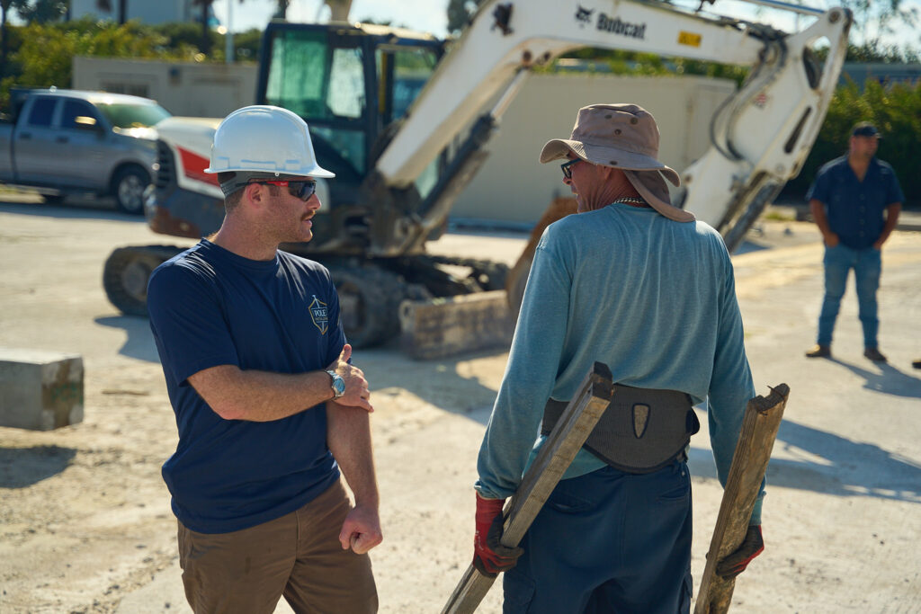 Pole Installers crew talking beside an excavator on a job site