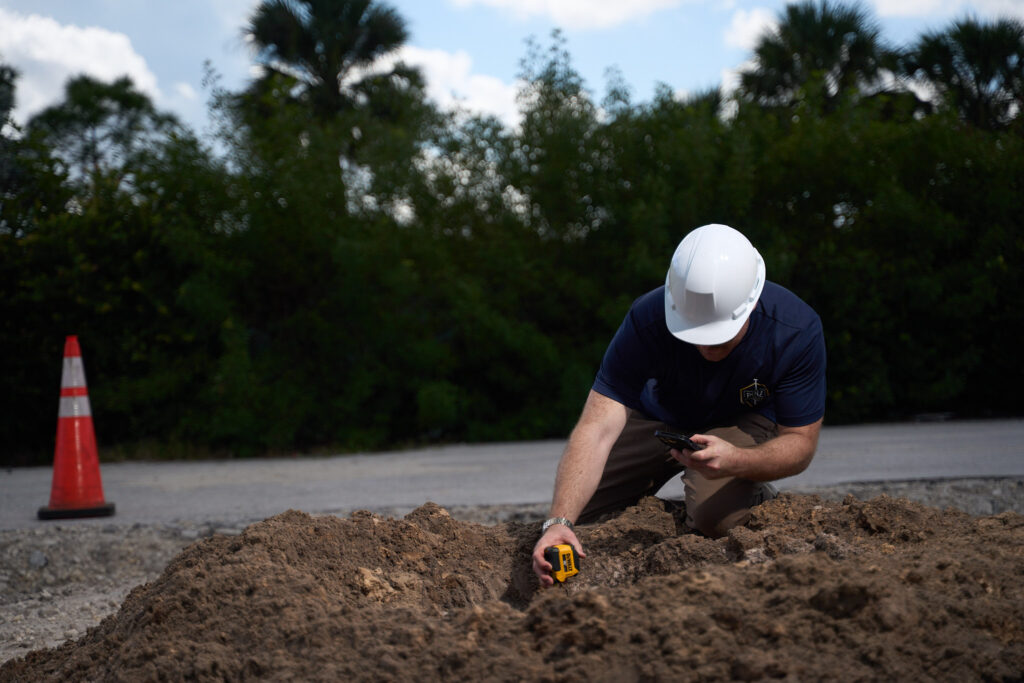 Pole Installers crew member checking a freshly drilled pole hole